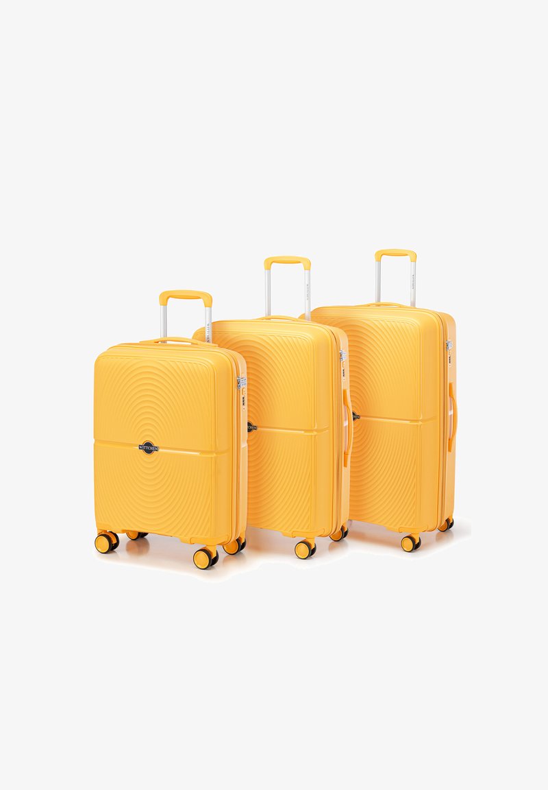 Set di tre valigie gialle rigide con motivi a onde in rilievo, manici telescopici e quattro ruote multidirezionali.