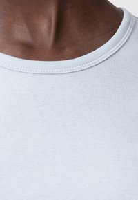 Jasnoniebieska koszulka typu crew-neck wykonana z miękkiej bawełny; posiada ribbed dekolt i gładką fakturę, podkreślając detale szwów.