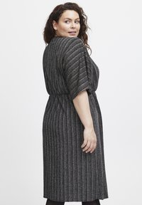 Svart och grårandig klänning med korta ärmar, en midja med bälte och knälång längd, med ett strukturerat, elastiskt tyg.