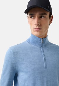 Helles blaues Sweatshirt mit Reißverschluss am Hals aus weichem Stoff und geripptem Kragen. Verfügt über einen kurzen Reißverschluss und eine figurnahe Passform.