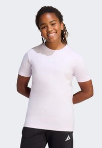 Jasnoróżowa koszulka krótki rękaw z okrągłym dekoltem i subtelnym detalem z logo z przodu. Wykonana z miękkiego materiału, o luźnym kroju.