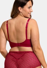 Soutien-gorge magenta à armatures avec bretelles réglables et dentelle, associé à un short en dentelle transparente assorti avec un motif diagonal.
