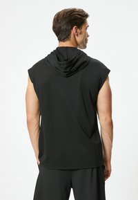 Schwarze ärmellose Kapuzenjacke aus glattem Stoff. Verfügt über einen lockeren Schnitt und minimalistisches Design, ideal für legere Outfits und zum Layering.