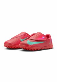 Zapatillas de fútbol rojas brillantes con un upper texturizado, que presentan un swoosh verde de Nike y un diseño de tipo slip-on. La suela tiene tacos moldeados para mayor tracción.