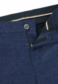 Navy blue trousers with a textured fabric, featuring a button closure and zip fly. Interior has a contrasting stripe pattern.