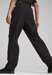 Zwarte cargo broek van lichtgewicht stof, met een elastische tailleband, zijzakken en een relaxte pasvorm, die het functionele ontwerp benadrukken.