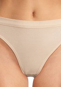 Mutande bikini in cotone beige con una texture liscia, dotate di un ampio elastico in vita e cuciture minime per un design aderente.