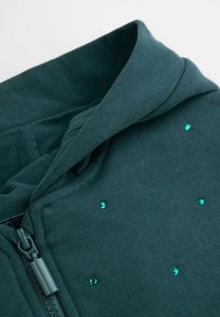 Ciemnozielona bluza z kapturem na zamek, wykonana z tkanej tkaniny, o miękkiej fakturze i ozdobiona rozrzuconymi akcentami w kolorze turkusowym.