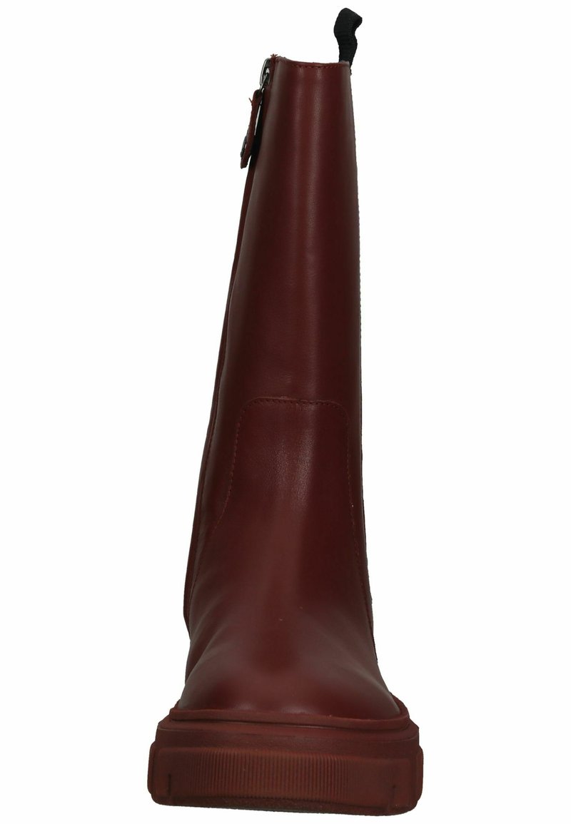 Botín de cuero burdeos con textura suave, punta redonda y suela de goma gruesa. Cuenta con una cremallera en la parte trasera y un lazo para facilitar su colocación.