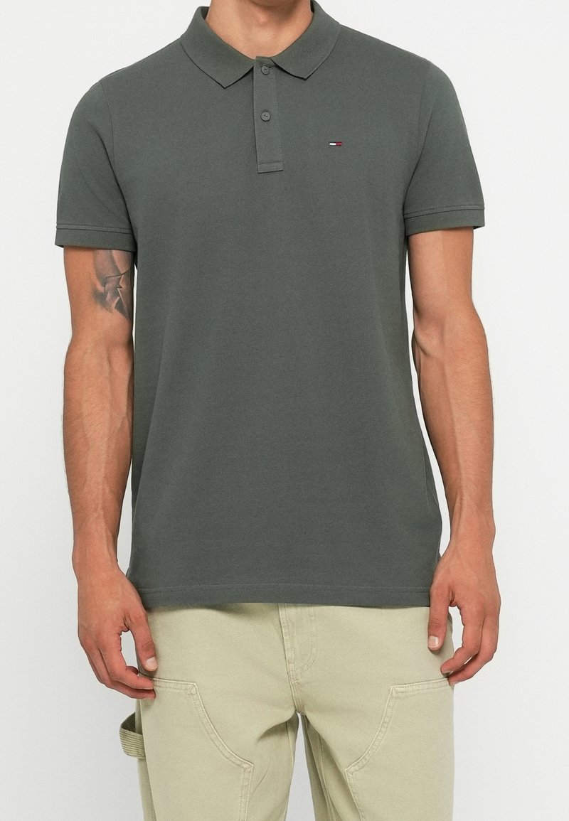 Dark grey polo shirt with a two-button placket and short sleeves, featuring a small embroidered logo on the left chest.
