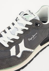 Baskets Pepe Jeans London grises et blanches avec lacets blancs, panneaux en daim texturé et tissu, et détails de la marque sur la languette et le côté.