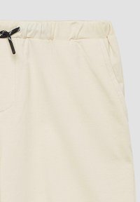 Beige Jogginghosen aus weichem Material, mit einem elastischen Bund und Kordelzug. Verfügt über Seitentaschen und eine glatte Textur.