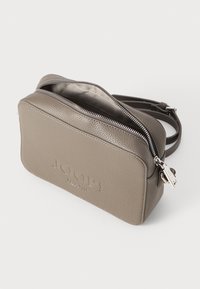 Borsa a tracolla in pelle grigia con superficie testurizzata, chiusura con zip e dettaglio del logo sul frontale. Include una tracolla regolabile.
