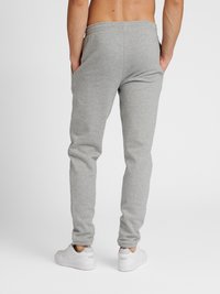 Grijze katoenen sweatpants met een elastische tailleband en zakken, taps toelopende broekspijpen en ribgebreide boorden, gecombineerd met witte sportschoenen.