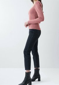 Rosa ribbad långärmad topp med fyrkantig halsringning, matchad med svarta raka jeans och svarta klackiga ankelboots.