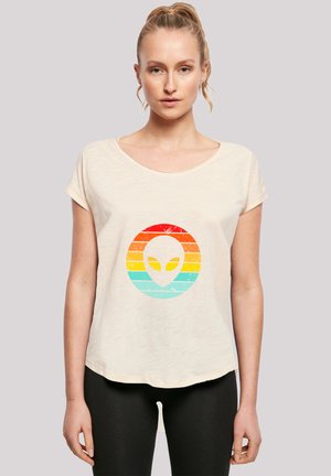 Light beige short-sleeve t-shirt featuring a retro alien graphic in red, orange, yellow, and blue striped circle design. Soft texture, relaxed fit.