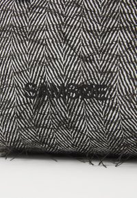 Tissu noir et blanc à motifs avec un design en zigzag, intégrant subtilement le nom de la marque « SANSOE » en fil noir.