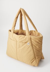 Borsa a spalla trapuntata in tessuto marrone chiaro, con due manici robusti, un ampio interno e un piccolo cartellino con logo sul lato.