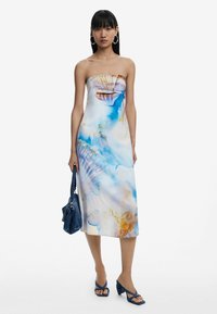 Ilma rihmadega midi kleit heledast kangast, millel on sinine ja oranž merekarbi muster. Koos tumeda teksakotiga ja siniste kontsakingadega.