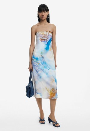 Strapless midi dress in light fabric featuring a blue and orange shell print. Paired with a dark denim bag and blue heeled sandals.