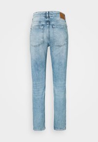 Jeans bleu clair à jambes droites vus de dos avec deux poches arrière et un patch en cuir marron sur la ceinture.