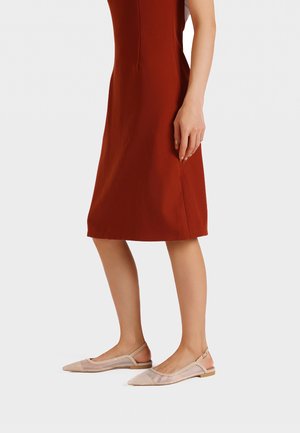 Slingback ballerina's in beige gaas met een spitse neus. Gecombineerd met een aansluitende rustkleurige jurk tot de knie met een soepele structuur en een naaddetail aan de zijkant.
