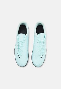 Light blue soccer shoes with a textured upper, black outsole, and tonal laces. Features a small black logo and pink accents on the sides.