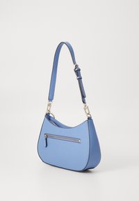 Bolsa de ombro em couro azul com uma forma curva, apresentando um bolso com fecho na parte da frente e uma alça ajustável com detalhes em metal.