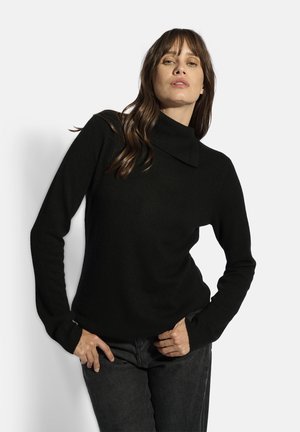 Pull à col roulé noir en tricot doux avec des manches longues et une coupe décontractée. Il présente des poignets côtelés et un col haut.