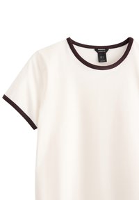 Creme t-shirt med rund halsudskæring og korte ærmer, der har en kontrasterende mørkebrun ribbede kant omkring kraven og ærmerne.