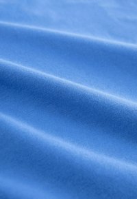 Weicher, glatter Stoff in lebhaftem Blau. Leichter Glanz mit subtiler Textur und gleichmäßiger Oberfläche, die gewellte Dimensionen in den Falten zeigt.