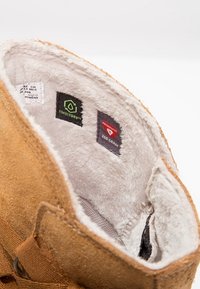 Bruine suède laars interieur met zachte, witte vachtvoering; bevat labels voor TimberDry en Primaloft isolatie, gelabeld 200 gram.