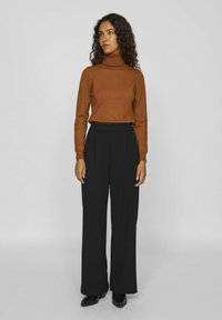 Un pull turtleneck marron et un pantalon large noir, tous deux en tissu doux. Le pull a une silhouette ajustée et un col côtelé.