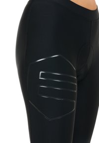 Black leggings with a smooth texture, featuring a glossy black geometric pattern on the thigh and a side pocket detail.