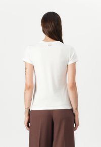 White short-sleeve t-shirt with rolled cuffs and a rounded neckline, featuring a small black "HUGO" logo on the upper back.