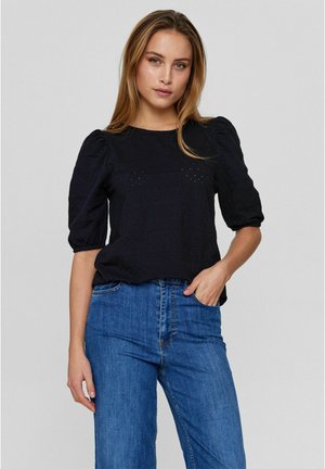 Schwarzes strukturiertes Oberteil mit puffärmel, kombiniert mit blauen Culottes.