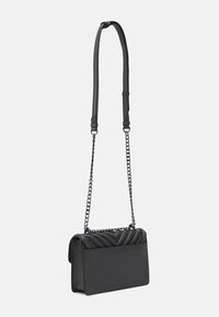 Borsa nera con un motivo a onda testurizzato sulla parte superiore, corpo rettangolare piatto e una lunga tracolla a catena regolabile.