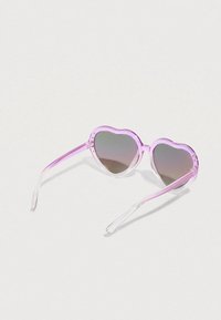 Γυαλιά ηλίου σε σχήμα καρδιάς με διάφανο ροζ σκελετό και σταδιακού γκρι φακούς. Τα μπράτσα έχουν διαφανές φινίρισμα.