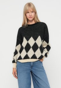 Fekete és krém színű, gyémántmintás pulóver, oversize szabás, puha tapintás, kötött anyag, kerek nyakkivágás, bordázott mandzsetta részletekkel.
