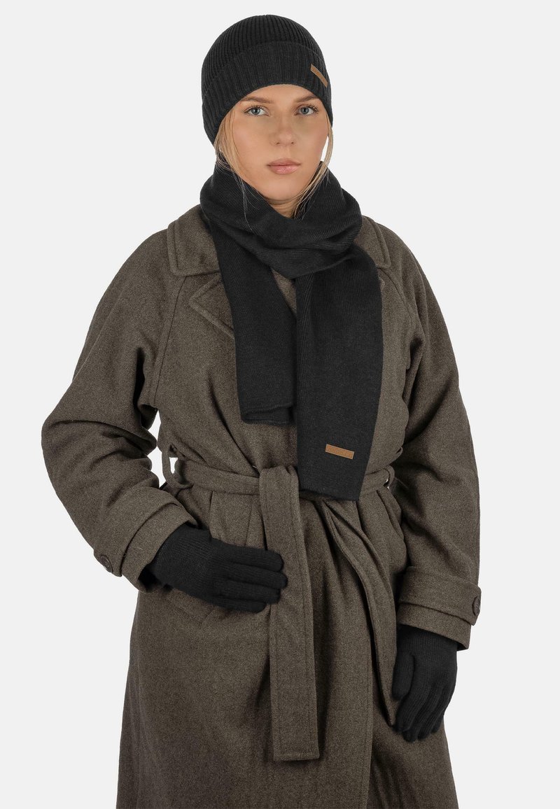 Black knitted beanie, scarf, and gloves with a textured finish, paired with a grey wool coat featuring a belt and buttoned cuffs.