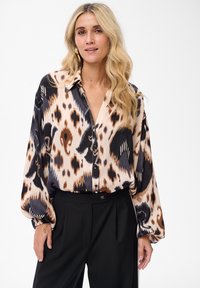 Long-sleeve, button-up blouse featuring a leopard print pattern in shades of brown, cream, and black. Soft fabric with a loose fit.