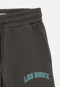 Σκούρο γκρι φόρμες με μαλακή υφή, ελαστική μέση και μπλε κεντημένο κείμενο "LES DEUX" στο αριστερό πόδι.