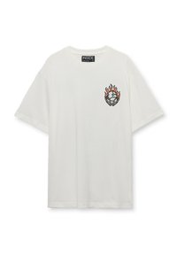 Camiseta blanca de algodón con mangas cortas, que presenta un diseño gráfico de llamas y un globo en el área del pecho izquierdo. Cuello redondo.
