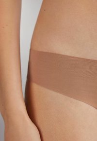 Bruine naadloze stoffen tailleband van ondergoed, zachte textuur, rustend tegen de huid, met een gladde afwerking en zonder zichtbare patronen of hardware.