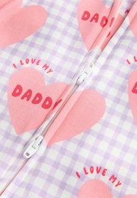 Ein Overall mit Reißverschluss, der ein rosa Herzmuster auf einem lavendelfarbenen karierten Hintergrund zeigt, mit dem Text "Ich liebe meinen PAPA" in fettem Rot. Weicher Stoff.