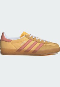 Zapatillas Adidas Gazelle en amarillo y rosa con un diseño de ante y sintético, cordones blancos y una lengüeta texturizada amarilla con el logo.