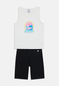 Vit linne med en färgglad "Hawaii" grafik och ett vågmönster, tillsammans med figurnära svarta shorts, båda i mjukt material.