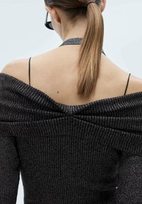 Off-shoulder zwarte gebreide top met geribbelde textuur, zilveren draad en een gedrapeerde rug. Smalle zwarte bandjes over de schouders.