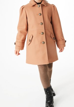 Persikofarvet uldfrakke med krave, fire frontknapper, to sidelommer og puffede ærmer, parret med ribbet brune leggings og sorte støvler.