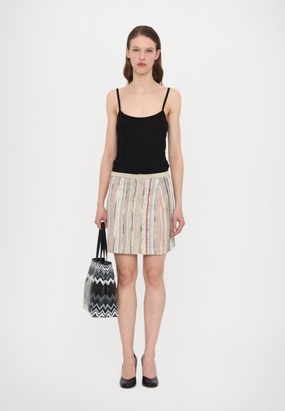 Black tank top with spaghetti straps, multi-colored striped skirt with buttons, and a black and white zigzag-patterned tote bag.